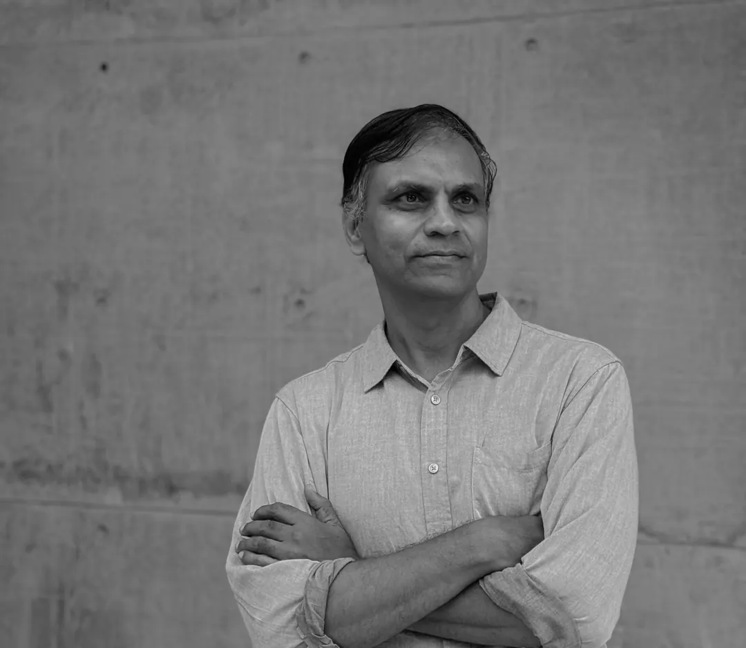 Hiren Patel, black and white portrait, arms folded against a concrete wall.