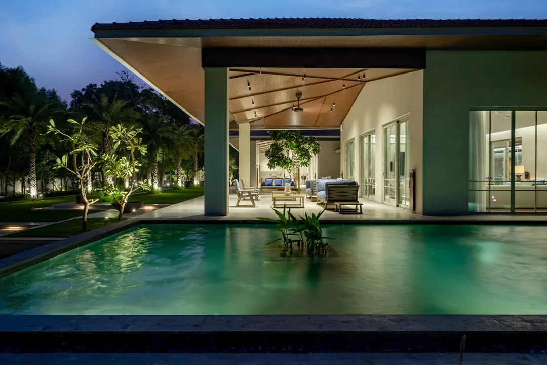 The same living pavilion as built, beside its pool at blue hour.