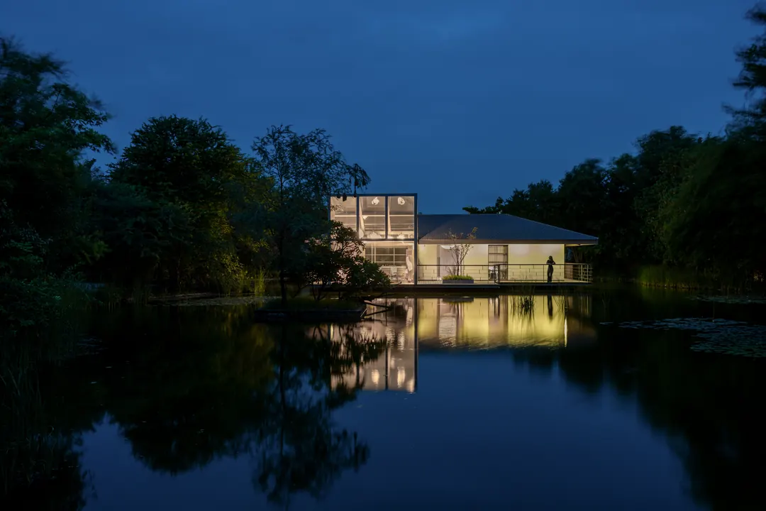 The lake house at Monkey Forest lit at blue hour, mirrored in the lake, the forest around it.